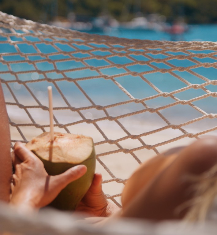 Guest relaxing in a beachside hammock under palm trees at The Inn at English Harbour, Antigua